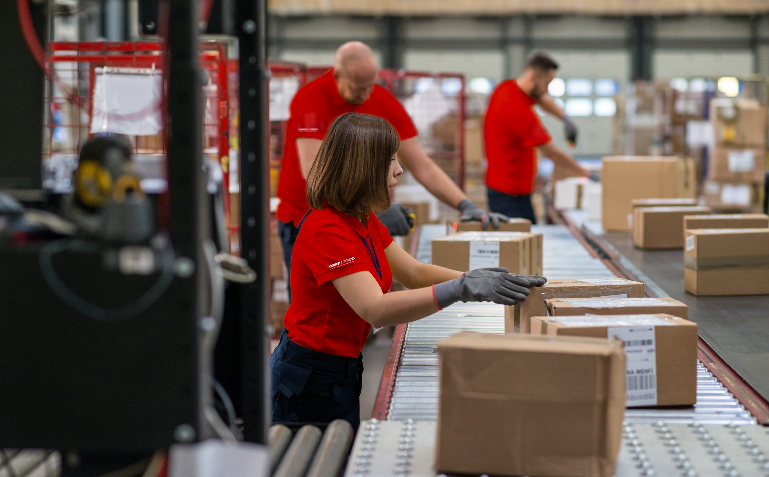 Warehouse associates scanning packages on conveyor belt